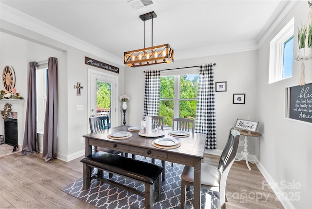 dining area featuring healthy amount of natural light, baseboards, crown molding, and light wood-type flooring
