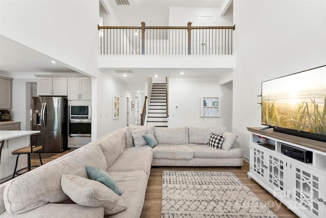 living room with stairway, a towering ceiling, wood finished floors, and baseboards