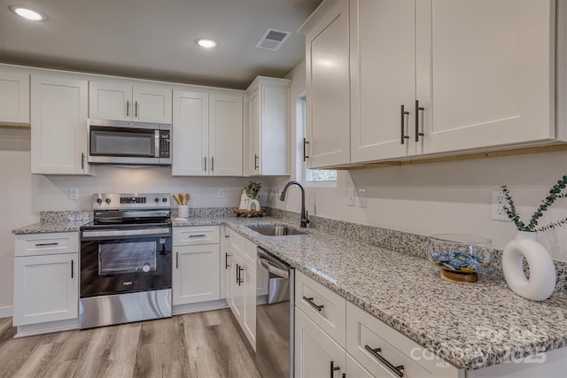721 32nd St NE, Conover, NC 28613 - kitchen with stainless steel appliances, light wood finished floors, a sink, white cabinetry, and visible vents