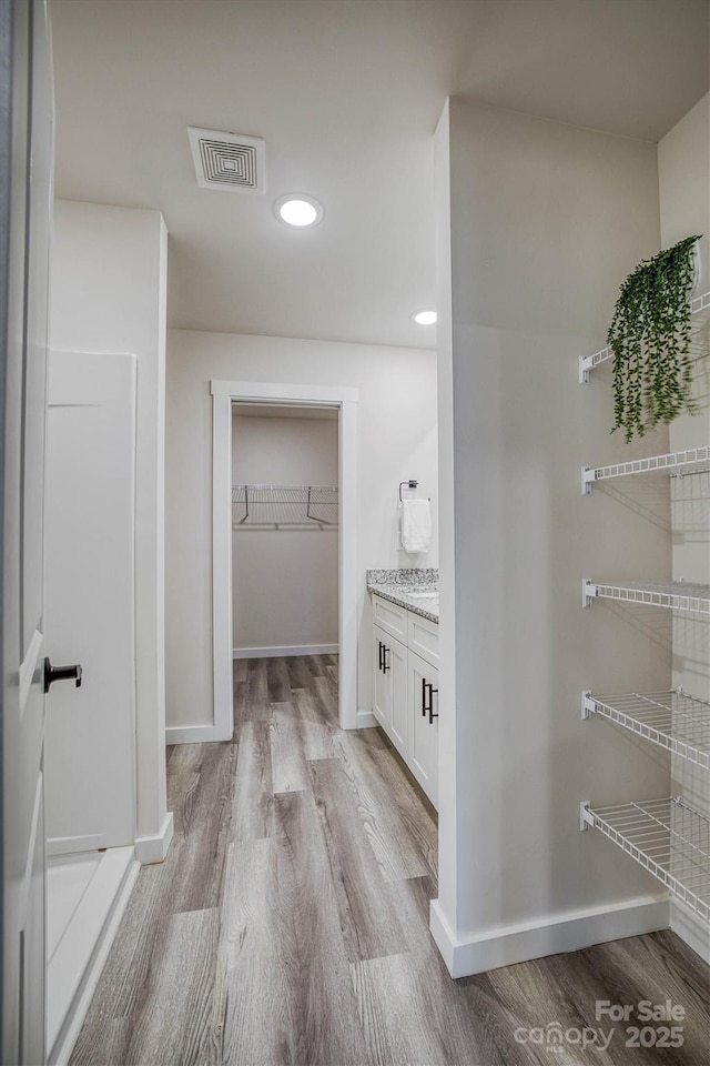 721 32nd St NE, Conover, NC 28613 - bathroom with visible vents, baseboards, wood finished floors, vanity, and a walk in closet