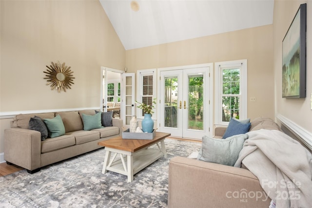 living area with high vaulted ceiling, wood finished floors, and french doors