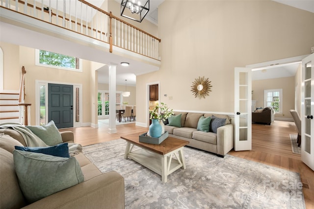 living area with wood finished floors, a chandelier, baseboards, a high ceiling, and french doors
