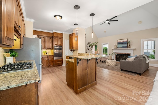 kitchen featuring light wood finished floors, brown cabinetry, a breakfast bar area, a peninsula, and plenty of natural light