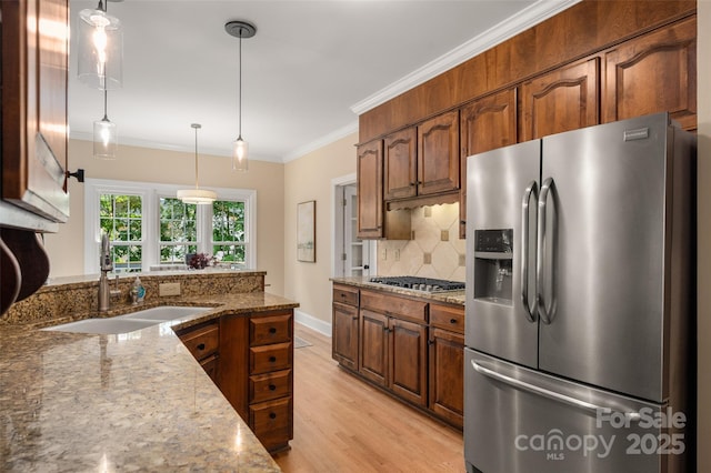 kitchen with a sink, light stone counters, stainless steel appliances, and decorative backsplash