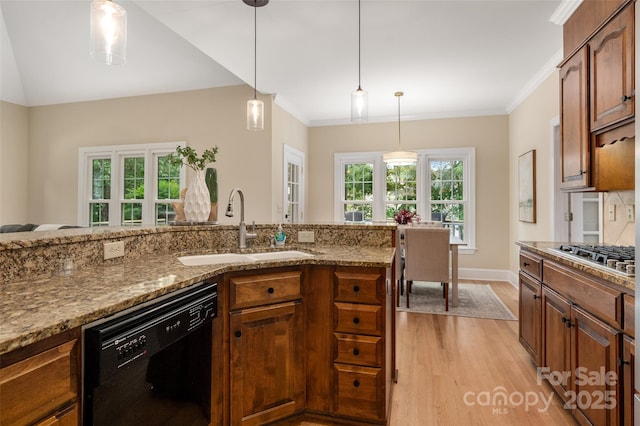 kitchen featuring stainless steel gas cooktop, light wood finished floors, a sink, light stone countertops, and black dishwasher