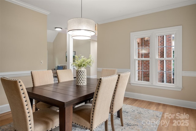 dining space featuring baseboards, light wood-type flooring, and crown molding