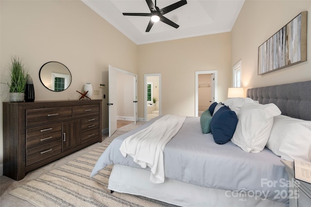 bedroom featuring light colored carpet, a high ceiling, multiple windows, and ensuite bathroom