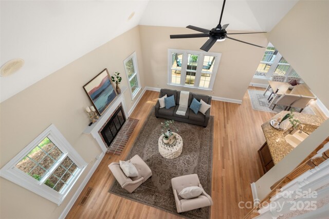 living area with high vaulted ceiling, baseboards, wood finished floors, and a fireplace