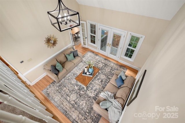 living room with a chandelier, wood finished floors, french doors, and baseboards