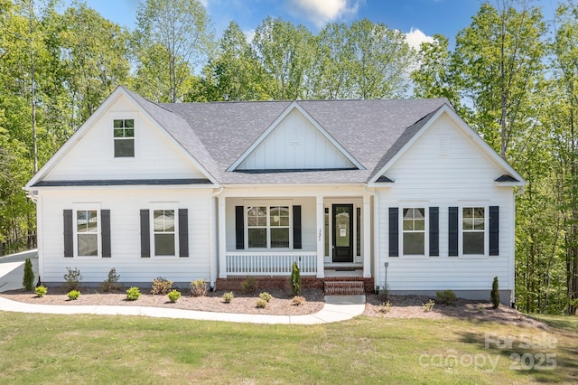view of front of home featuring a shingled roof, covered porch, board and batten siding, and a front yard
