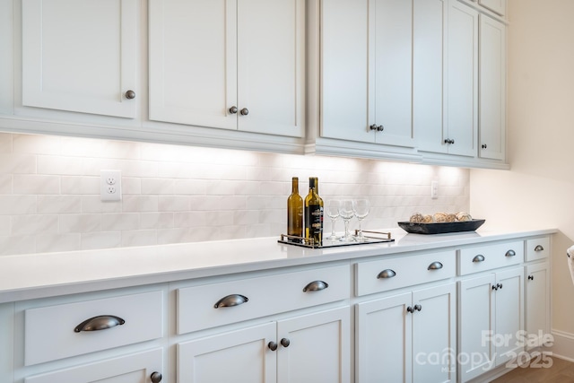 kitchen featuring light countertops, backsplash, and white cabinetry
