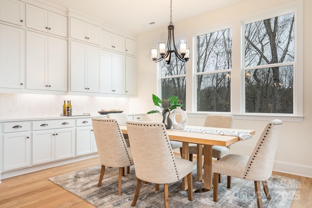 dining space with baseboards, a chandelier, visible vents, and light wood-type flooring