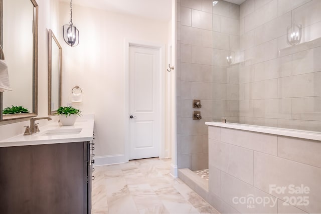 bathroom with a walk in shower, a sink, double vanity, marble finish floor, and baseboards