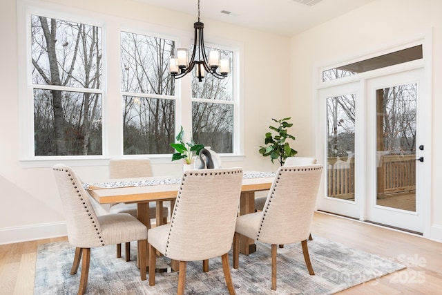 dining area with an inviting chandelier, baseboards, wood finished floors, and visible vents