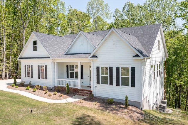 view of front of property with central AC, covered porch, a front yard, a shingled roof, and board and batten siding
