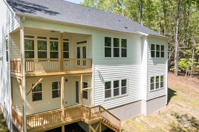 back of house featuring roof with shingles and a deck