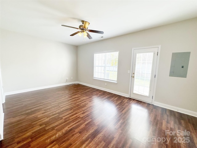 empty room with electric panel, baseboards, dark wood-type flooring, and ceiling fan