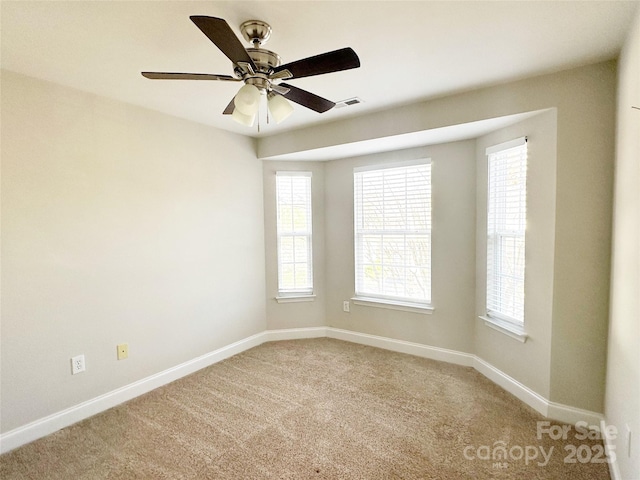 spare room featuring visible vents, a ceiling fan, baseboards, and light colored carpet
