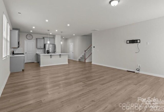 5024 Colline Ct, Charlotte, NC 28216 - unfurnished living room featuring light wood-style flooring, recessed lighting, baseboards, and stairs