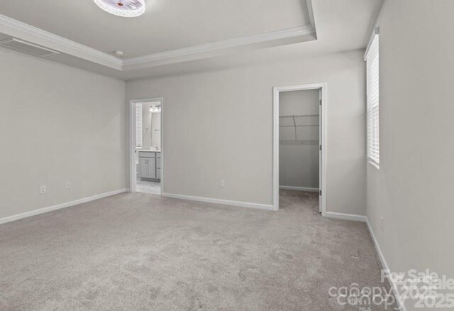 5024 Colline Ct, Charlotte, NC 28216 - unfurnished bedroom featuring a raised ceiling, a spacious closet, ornamental molding, carpet, and baseboards