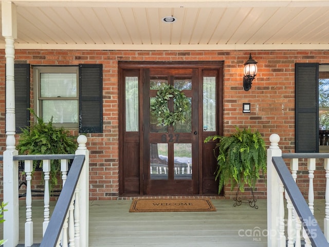 entrance to property featuring brick siding and covered porch