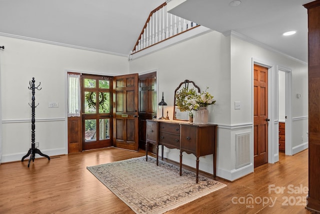 entrance foyer featuring wood finished floors, visible vents, baseboards, and ornamental molding