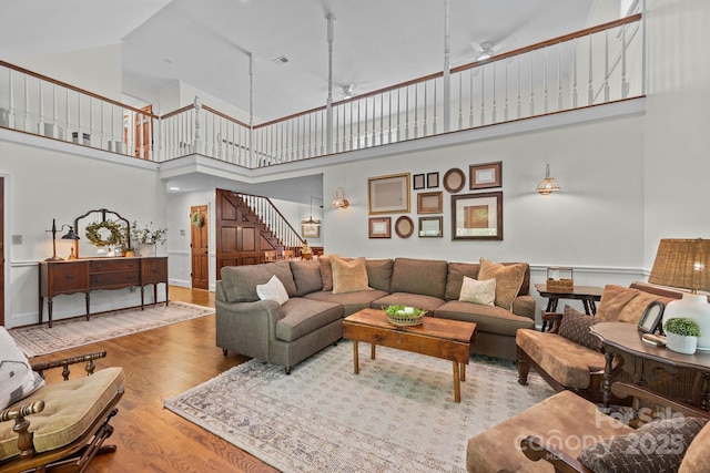 living room featuring wood finished floors, high vaulted ceiling, and stairway