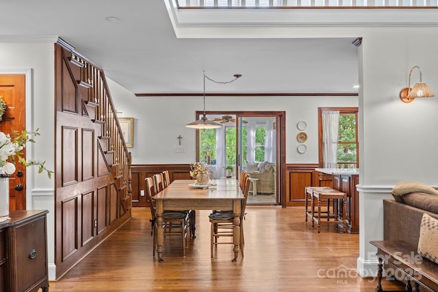 dining room featuring light wood-style floors, stairway, a wainscoted wall, and crown molding