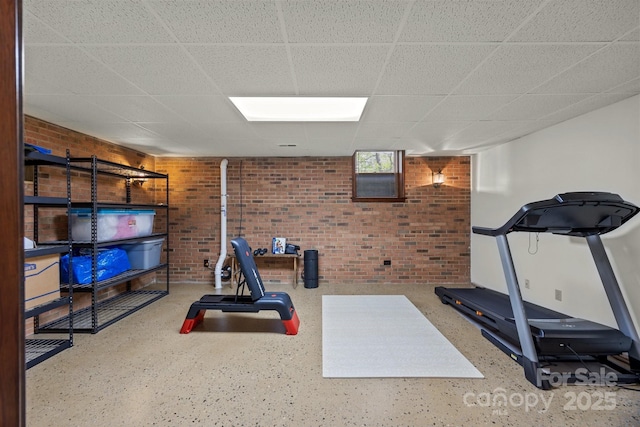 workout area featuring brick wall and a paneled ceiling