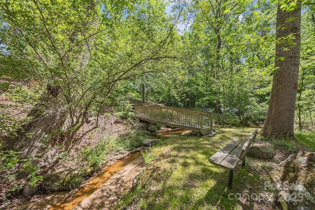 surrounding community featuring a wooden deck and a forest view