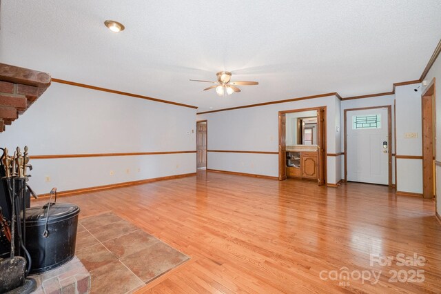 empty room featuring crown molding, a ceiling fan, baseboards, and light wood-style floors