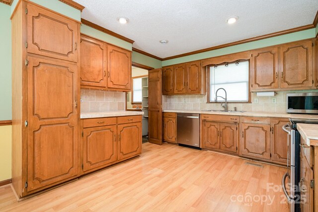 kitchen featuring visible vents, crown molding, appliances with stainless steel finishes, light countertops, and a sink