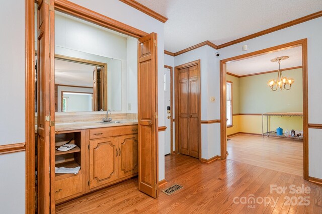 bathroom featuring crown molding, an inviting chandelier, wood finished floors, and visible vents