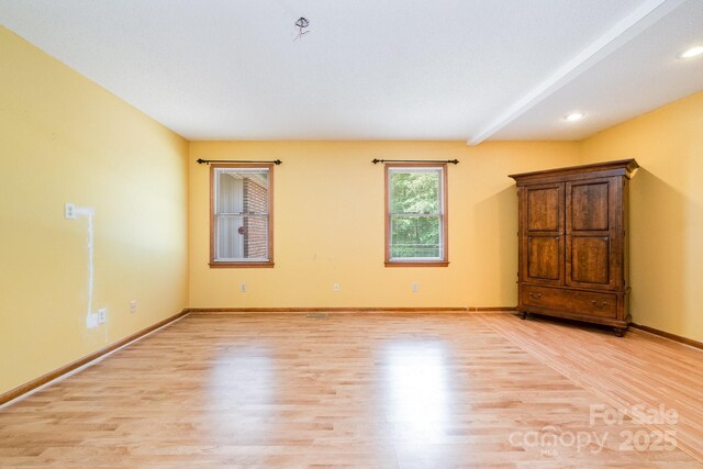 unfurnished room with recessed lighting, beamed ceiling, baseboards, and light wood-style floors
