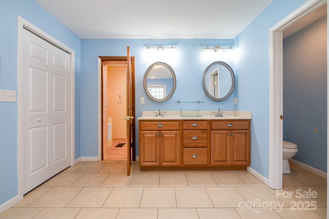 bathroom featuring a sink, tile patterned floors, toilet, and double vanity
