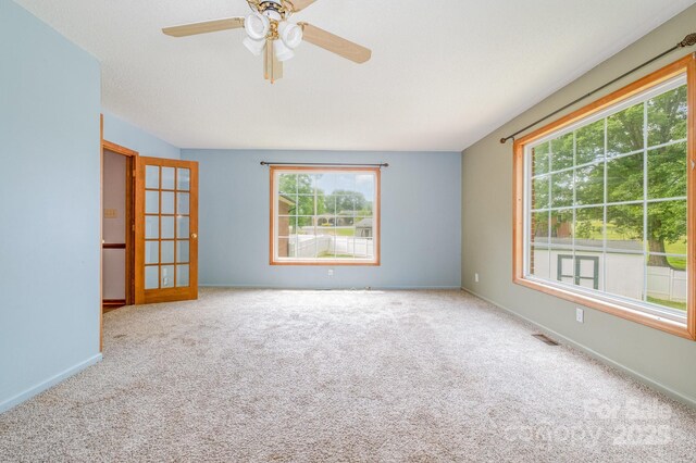 unfurnished room with a healthy amount of sunlight, carpet, and visible vents