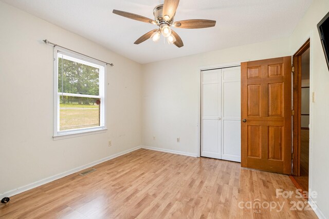 unfurnished bedroom featuring visible vents, light wood finished floors, baseboards, and a closet
