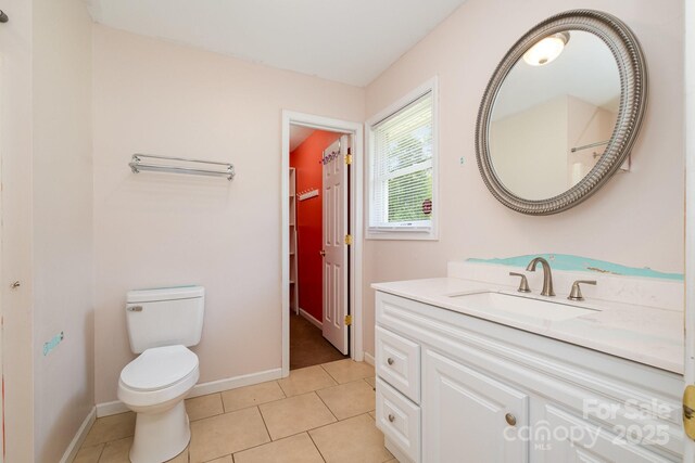 bathroom featuring vanity, baseboards, tile patterned flooring, and toilet