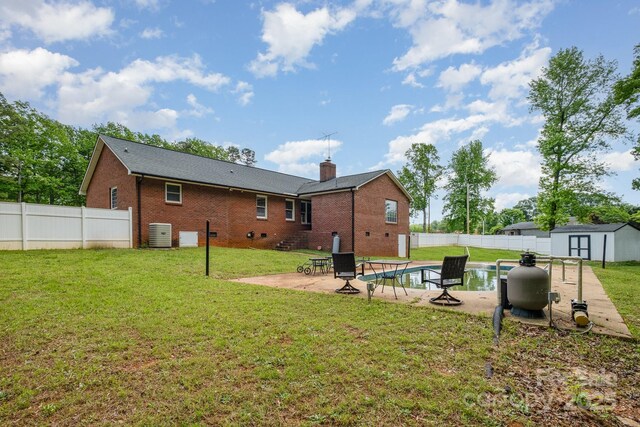 rear view of property with an outdoor structure, a fenced backyard, brick siding, a patio area, and a storage shed