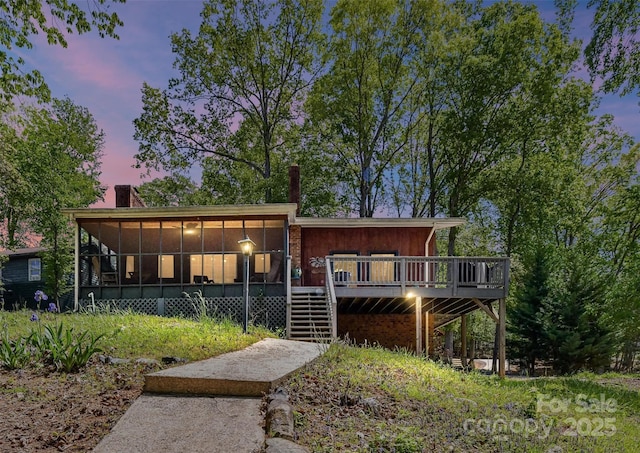 1278 Island Creek Dr, Troy, NC 27371 - back of house at dusk with a chimney, a wooden deck, a sunroom, and stairway