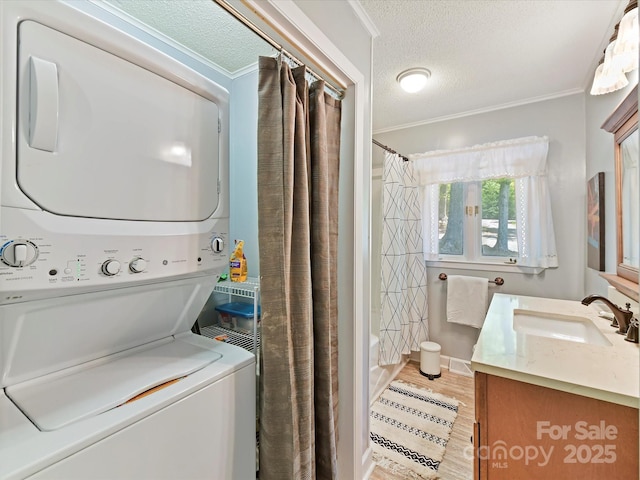 1278 Island Creek Dr, Troy, NC 27371 - clothes washing area with stacked washer and clothes dryer, a textured ceiling, crown molding, and a sink