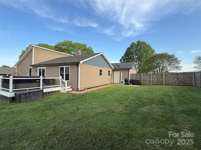 rear view of house with a wooden deck, a lawn, a chimney, and a fenced backyard