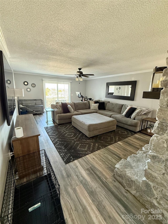 living room with a ceiling fan, wood finished floors, a textured ceiling, and ornamental molding