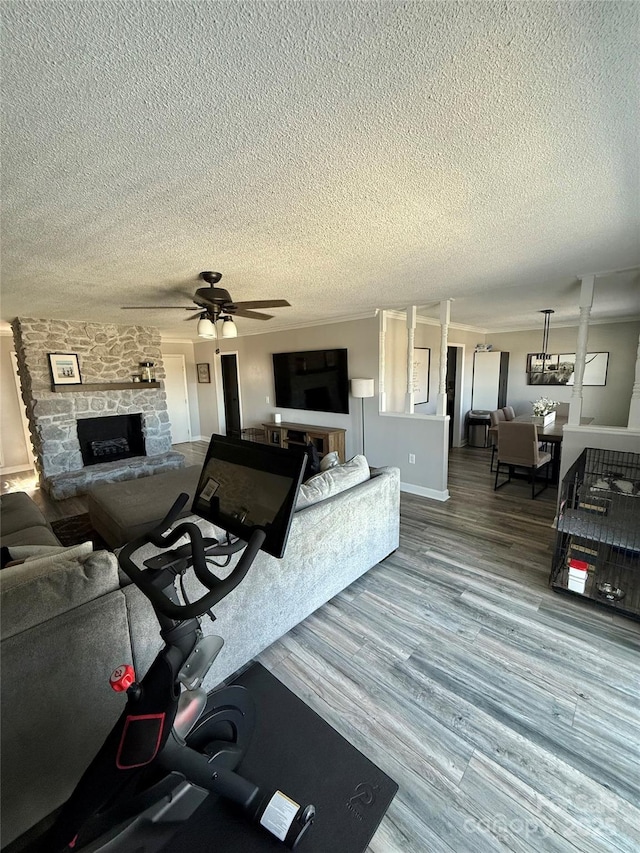living room featuring a fireplace, wood finished floors, a textured ceiling, and ceiling fan