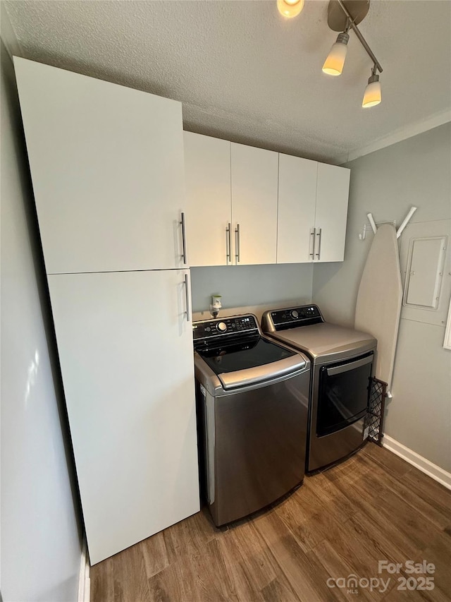 clothes washing area featuring cabinet space, light wood-type flooring, a textured ceiling, and washer and dryer