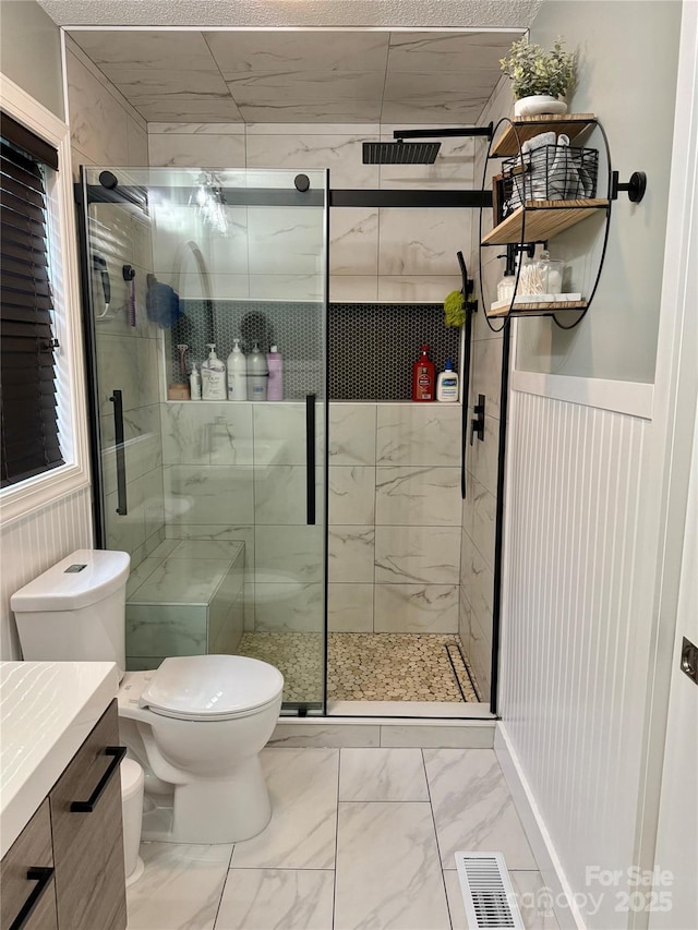 full bathroom with a shower stall, vanity, marble finish floor, toilet, and visible vents