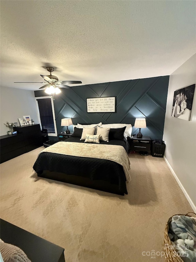 carpeted bedroom with a decorative wall, a textured ceiling, baseboards, and ceiling fan