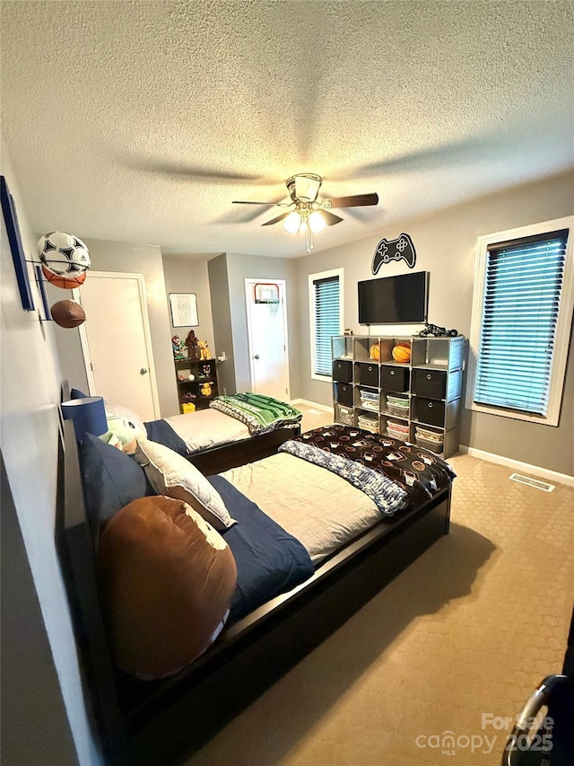 bedroom with carpet, baseboards, visible vents, a ceiling fan, and a textured ceiling