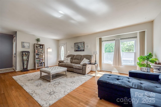 living area with baseboards, a healthy amount of sunlight, and hardwood / wood-style floors