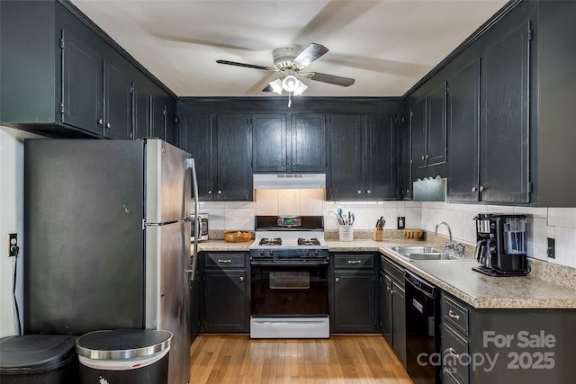 kitchen with a sink, freestanding refrigerator, gas range, black dishwasher, and under cabinet range hood